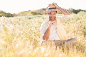 طرد الأوهام -A tranquil man sitting peacefully in a hat amidst a field.