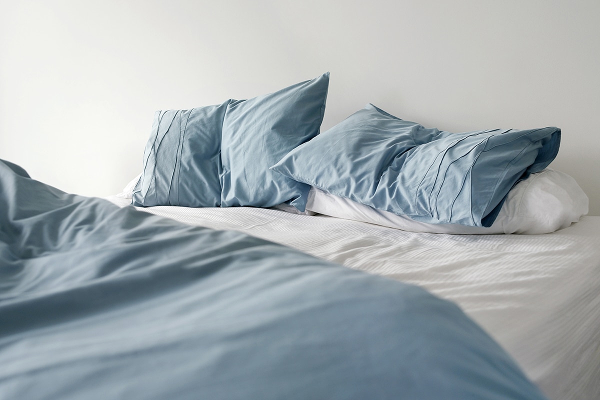 علاج شلل النوم -Blue duvet cover on a white bed with انفراج.