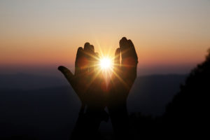 A person's hands reaching up to the sun at sunset symbolizing the return of a natural life after the invasion of obsessive purity.