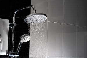 وسواس النظافة والطهارة-A shower head is shown in a black and white tiled bathroom, evoking childhood fear.