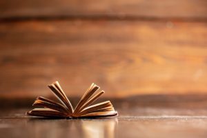 أفكار سوداوية An open book on a wooden table, showcasing distant thoughts.