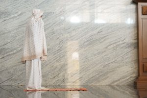 أصوات البطن-A muslim woman standing in front of a marble wall, representing a new dawn after painful distress.