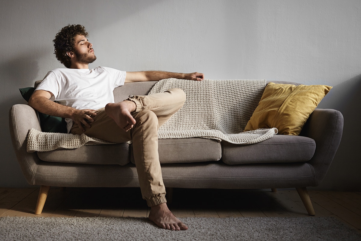 قصة عن الاكتئاب-A man sitting on a couch in front of a window, reflecting on the end of their relationship.