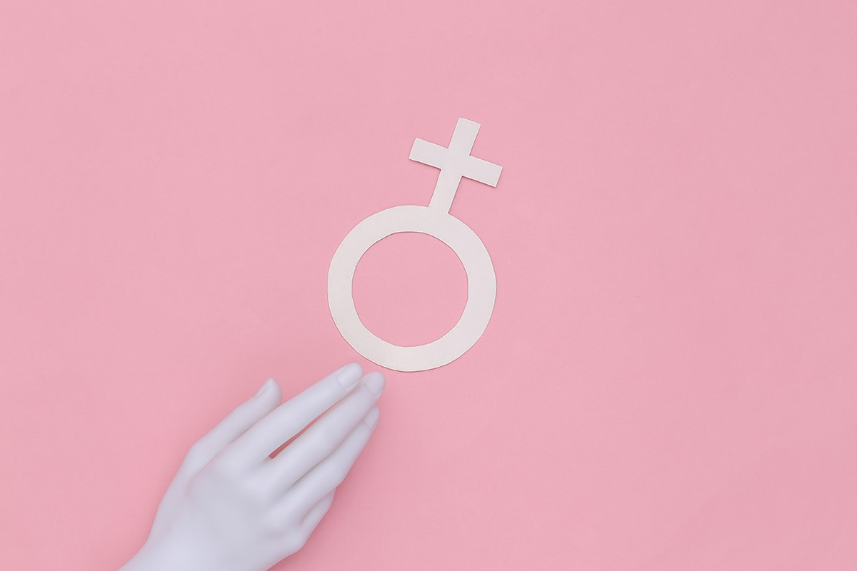 المجاهدة النفسية-A woman's hand holding a female symbol on a pink background, depicting psychological empowerment and self-conviction.