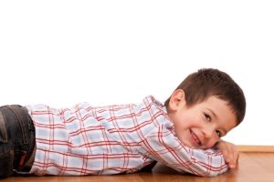 قصة عن التخلص من القلق -A determined young boy laying on a wooden floor, demonstrating psychological resilience.