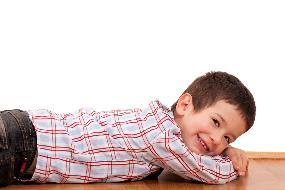 قصة عن التخلص من القلق -A determined young boy laying on a wooden floor, demonstrating psychological resilience.