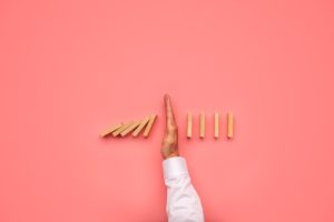 انفصال الوالدين - A businessman's hand confidently holds a stack of dominoes on a vibrant pink background.