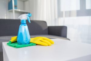 تعديل السلوك- A pair of yellow gloves, displaying القرار الشجاع, resting next to a bottle of cleaning spray on a table.