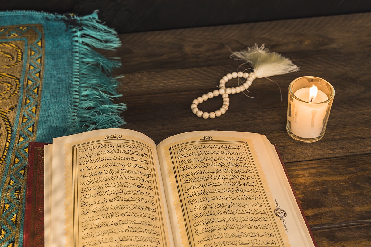 انتباه الوالدين أعاد عقيدتها - A candle on a wooden table with a muslim book emphasizing parental attention and belief.