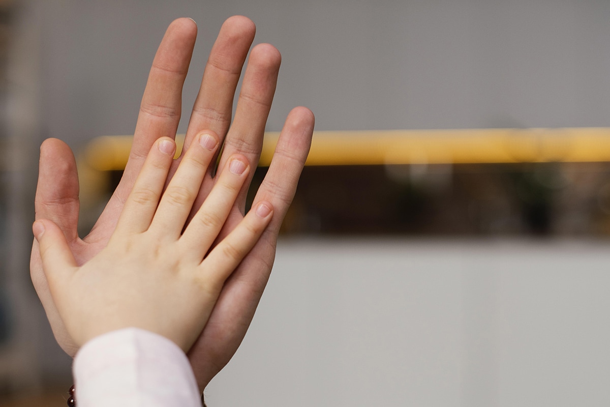 عادة قضم الأظافر : الحنان يغير السلوك A woman and a child are holding hands in a room, emphasizing parental attention.