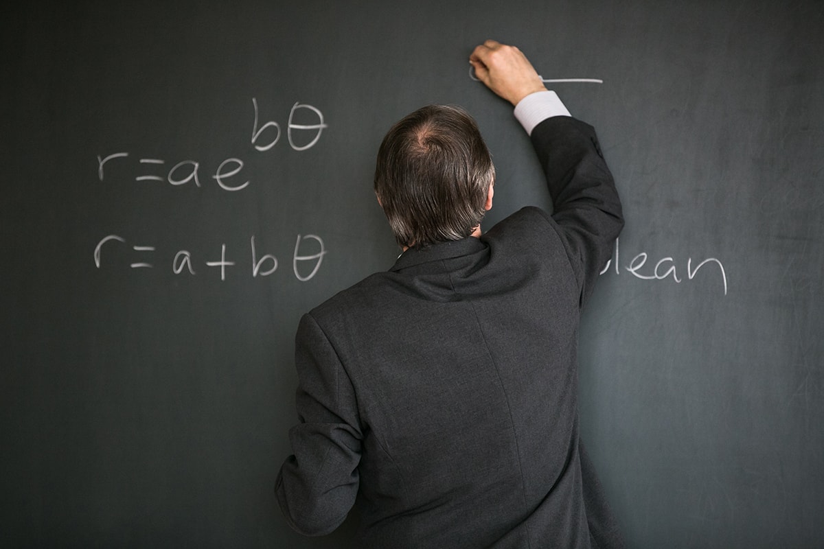 A man in a suit writing on a blackboard while gaining parents' attention. مواجهة الابتزاز