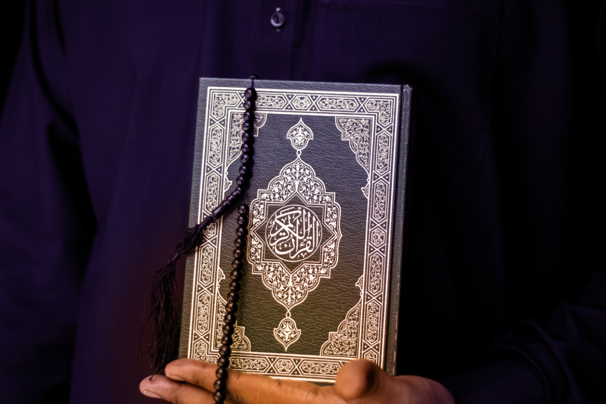 Man Holding Quran. Islamic Background. Arabic on the cover trans